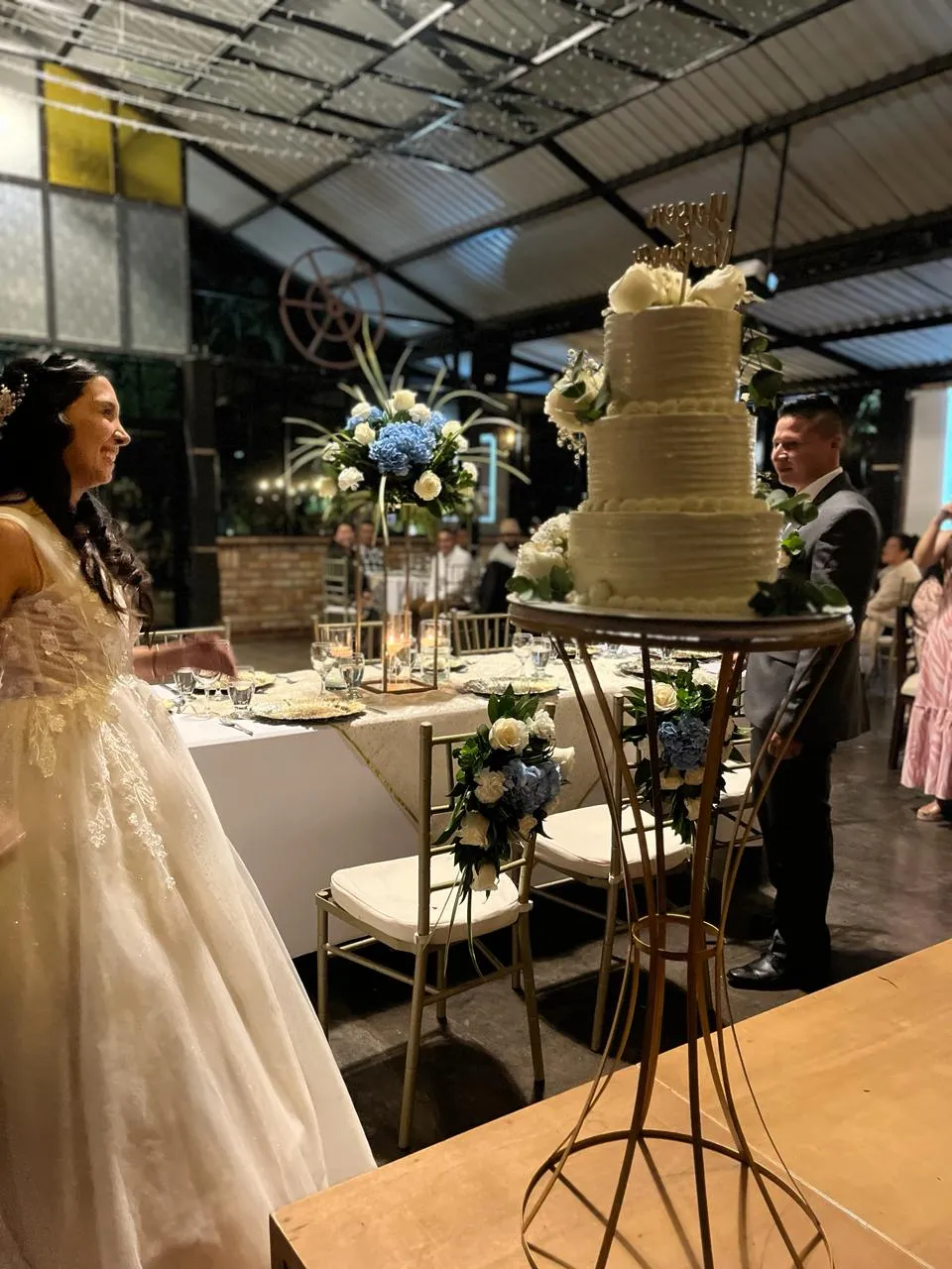 Pastel de bodas de tres pisos decorado con flores azules y blancas